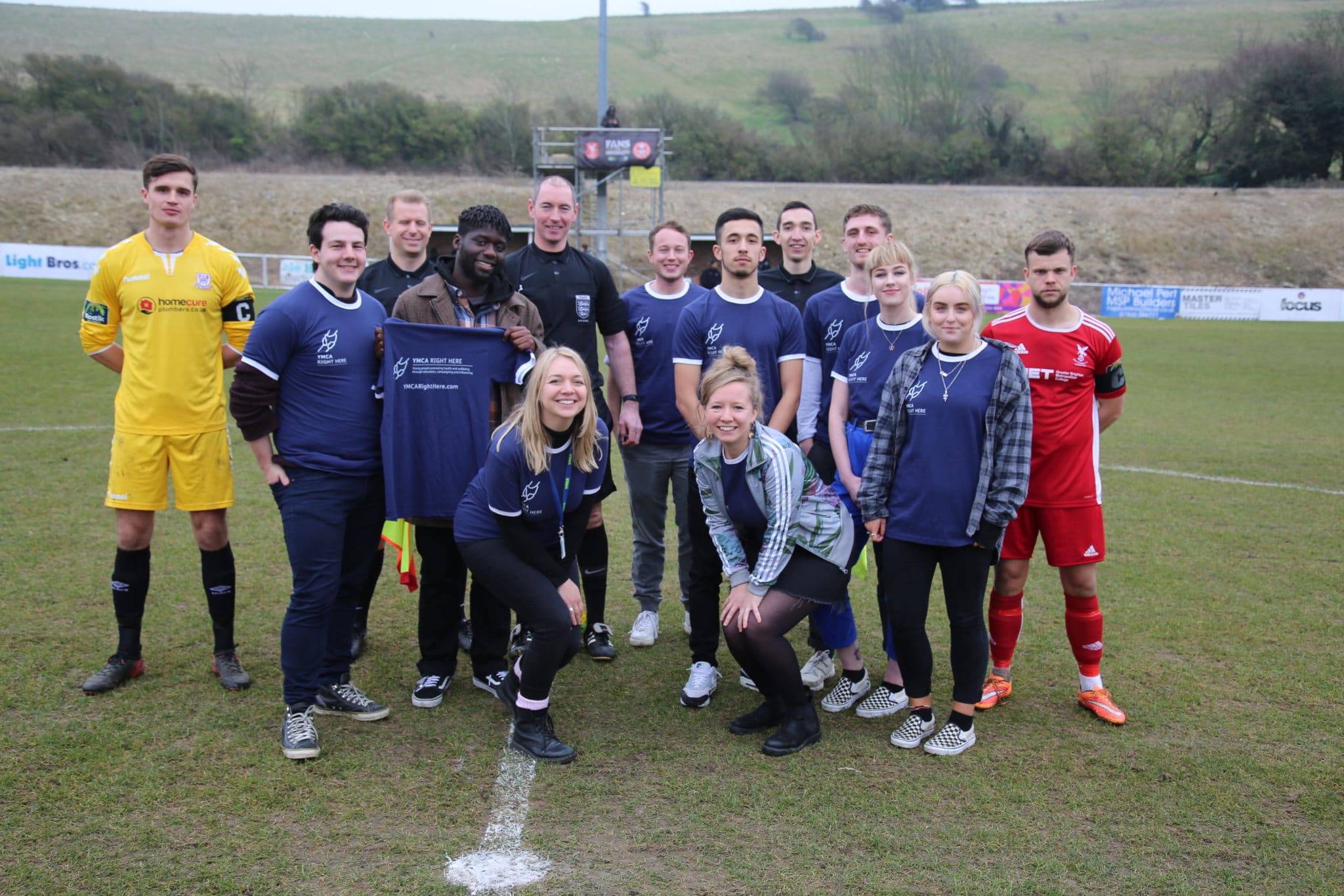 Photo of footballers and staff on football pitch
