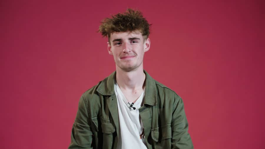 Connor smiling in front of a pink background