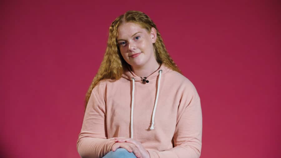 Chloe smiling in front a pink background