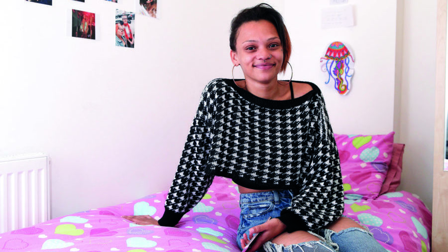 young woman sits on bed in supported accommodation