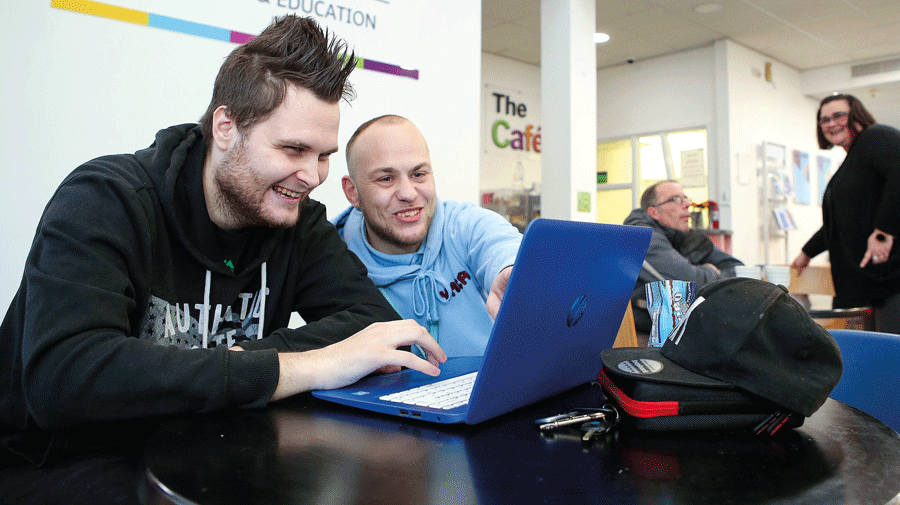 YMCA worker helps young person on laptop